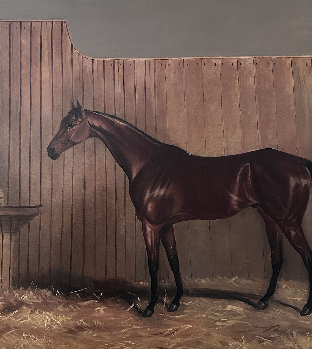 An oil painting depicting a bay racehorse standing in profile inside a wooden stable stall lined with straw. View IV