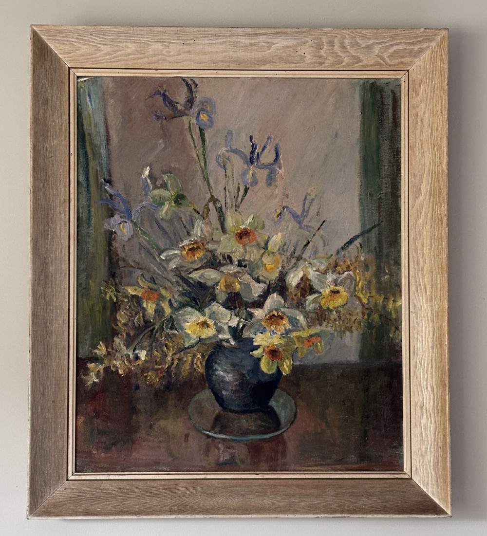 An oil painting on canvas depicting a ceramic vase filled with white daffodils and blue irises resting on a dark surface. View II