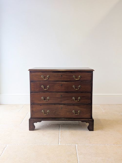 fig 1. An 18th-century George III mahogany chest of drawers featuring four graduated drawers with brass swan-neck handles and bracket feet.