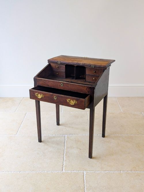 fig 1. A Georgian dark elm clerks desk featuring a sloped writing surface, brass escutcheons, brass handles, and square legs.