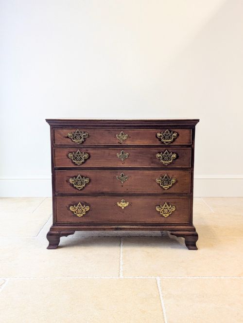 fig 1. An antique George II mahogany chest of drawers featuring four graduated drawers with ornate brass handles on bracket feet.