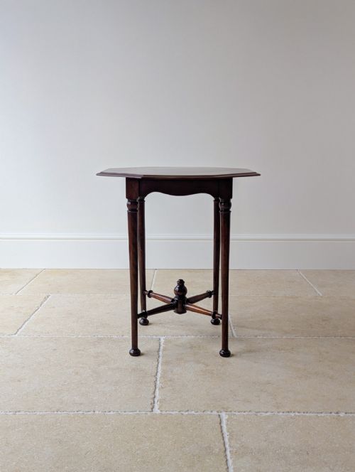 fig 1. An antique dark mahogany occasional table featuring an octagonal top, turned slender legs, shaped aprons, and a central finial on a cross stretcher.
