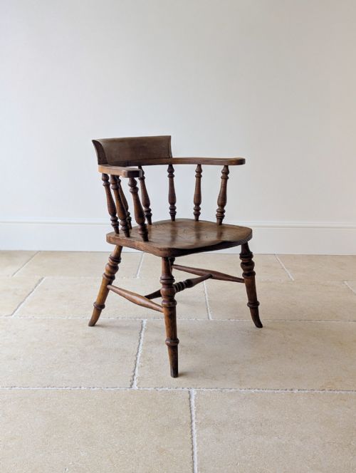 fig 1. A Victorian elm and beech captains desk chair featuring a curved backrail, turned spindles, a contoured saddle seat, and turned legs with a stretcher base.