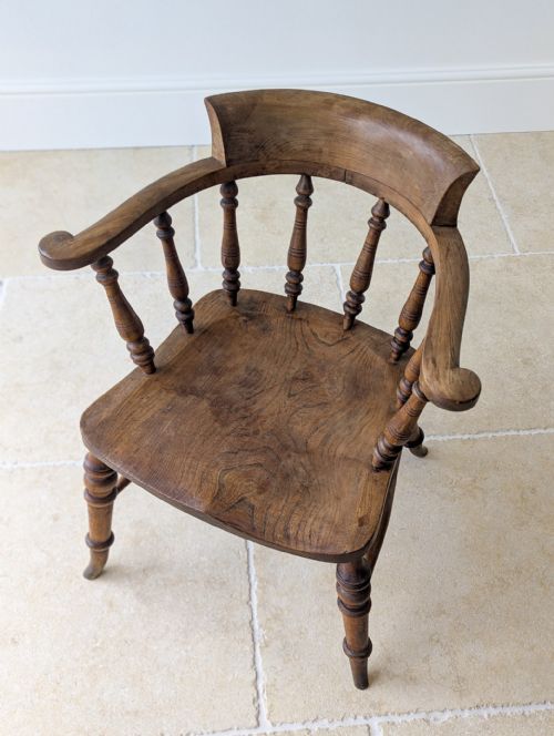 fig 2. A Victorian elm and beech captains desk chair featuring a curved backrail, turned spindles, a contoured saddle seat, and turned legs with a stretcher base.
