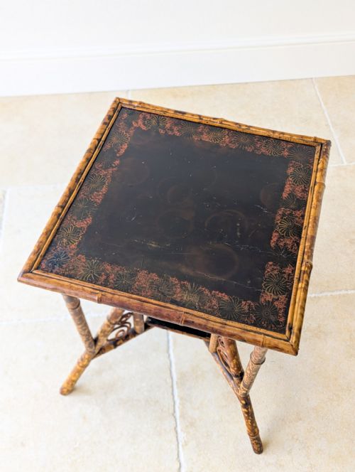 fig 1. A late 19th-century bamboo occasional table featuring a dark lacquered square top, tortoiseshell bamboo frame, decorative side scrollwork, and a lower square undertier.