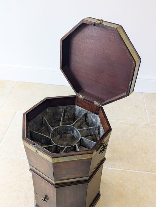 fig 1. An octagonal dark mahogany George III cellaret with brass binding bands, side handles, and a lower enclosure.