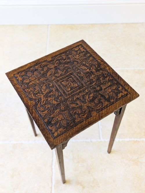 fig 1. An Edwardian dark oak occasional table featuring a relief-carved square top, shaped corner brackets, and four straight tapered legs.