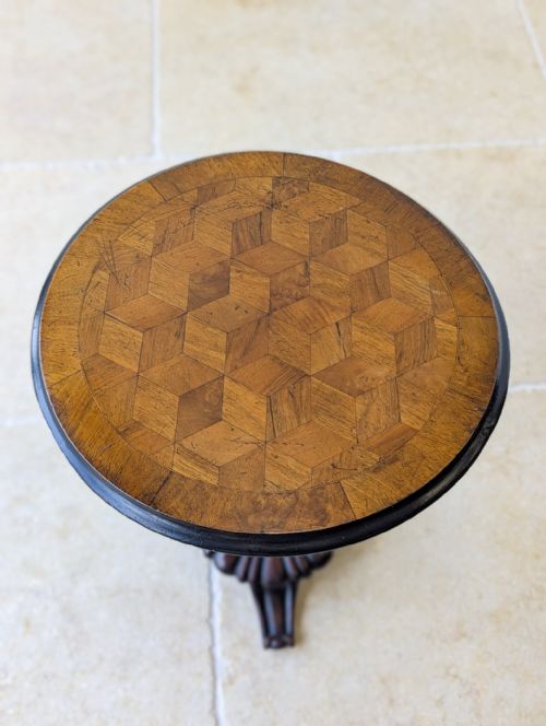 fig 1. An antique William IV walnut and mahogany wine table featuring a circular top with decorative marquetry, a fluted column, and a carved tripod base.