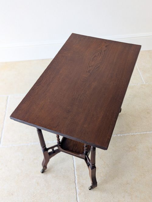 fig 2. A dark mahogany rectangular side table featuring fluted turned legs, a lower shelf tier, and brass castors.