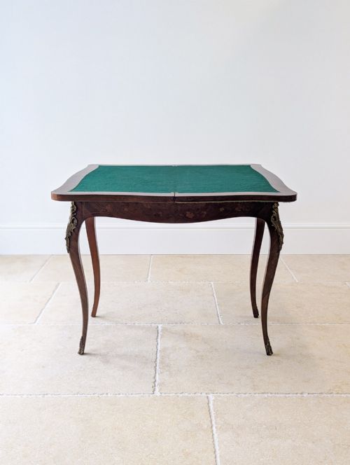 fig 1. A late 19th-century Louis XV style kingwood card table featuring floral marquetry inlays, serpentine edges, brass ormolu mounts, and slender cabriole legs.