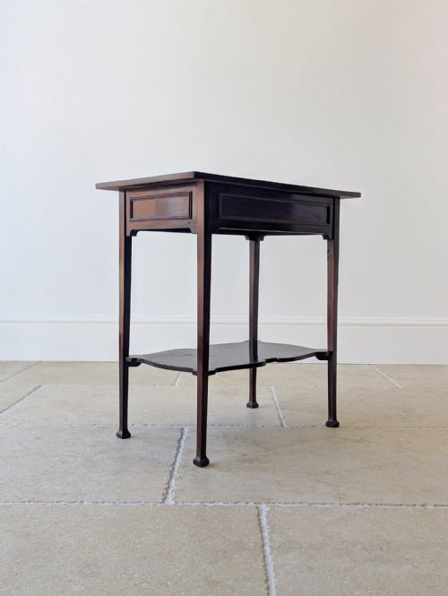 fig 1. An antique late Victorian dark mahogany side table featuring a flat rectangular surface, straight square legs, and a shaped lower undertier shelf.