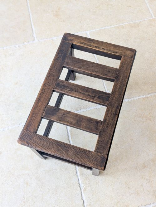 fig 1. An Edwardian dark oak luggage stand featuring a rectangular slatted top and straight square legs with supporting stretchers.