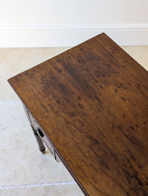 fig 1. An antique Regency mahogany kneehole writing table with three drawers, brass handles, and turned legs.