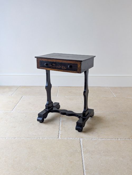 fig 2. An antique Regency ebonised work table featuring Chinoiserie artwork on the rectangular top, a single drawer, and trestle support legs.