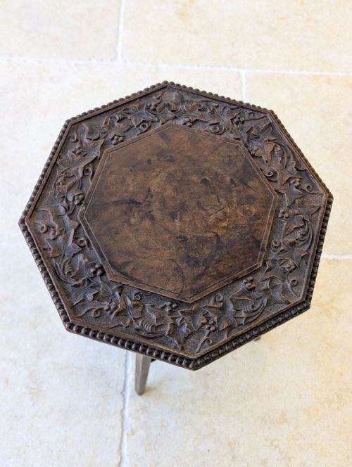 fig 1. An antique dark walnut octagonal occasional table featuring a carved outer border, splayed legs, and a lower square tier with incised geometric motifs.