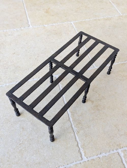 fig 1. A rectangular black wrought iron Georgian hearth footman featuring a slatted top grid supported by six turned baluster legs.