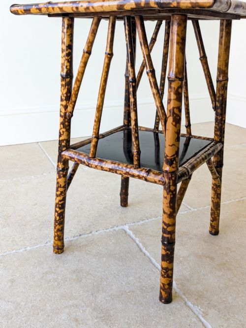 fig 1. A late 19th-century square bamboo occasional table featuring a dark lacquered top, a lower tier shelf, and a mottled tortoiseshell finish.
