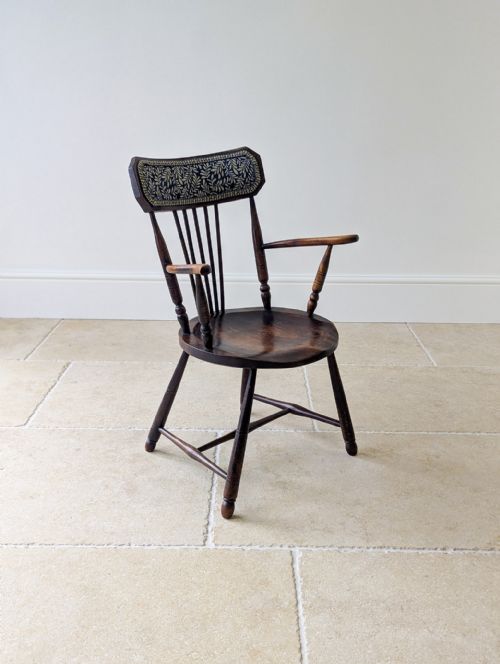 fig 1. A dark stained elm and beech Windsor armchair featuring turned legs, a shaped saddle seat, spindle back, and a patterned foliate crest rail.