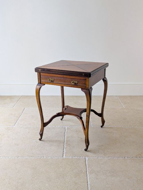 fig 1. An Edwardian mahogany envelope card table with open triangular leaves revealing a green baize top, cabriole legs, and brass castors.