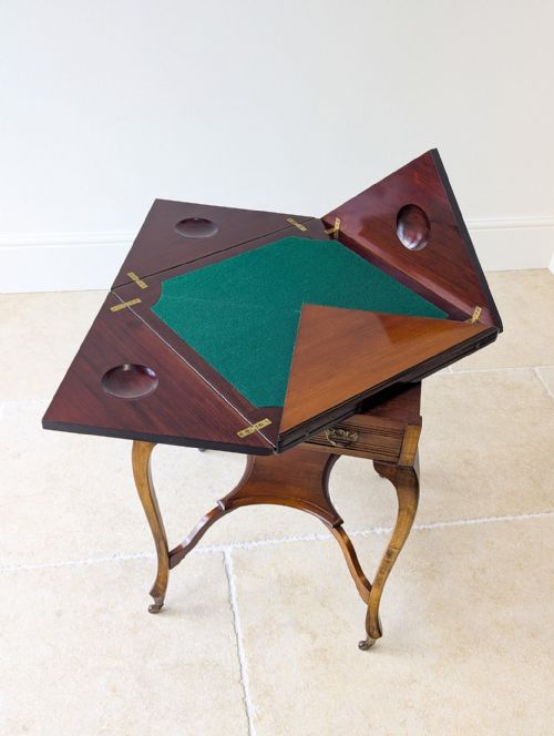 fig 2. An Edwardian mahogany envelope card table with open triangular leaves revealing a green baize top, cabriole legs, and brass castors.