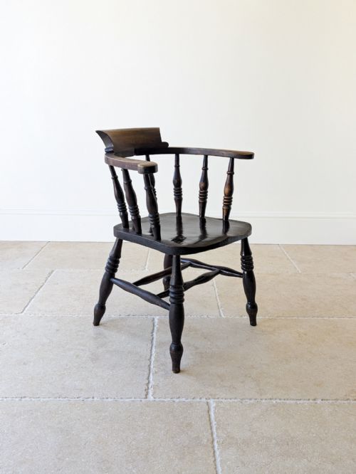 fig 1. A dark-stained Victorian elm and ash captains chair featuring a curved crest, turned vertical spindles, a contoured seat, and turned legs joined by an H-stretcher.