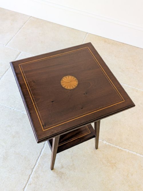 fig 1. An Edwardian dark mahogany occasional table featuring a square top with satinwood line inlay, splayed legs, and a square lower shelf.