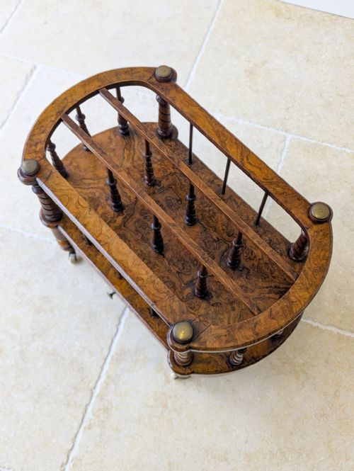 fig 1. A Victorian burr walnut Canterbury featuring turned barley-twist spindles, brass support rails, a lower single drawer, and small castors.