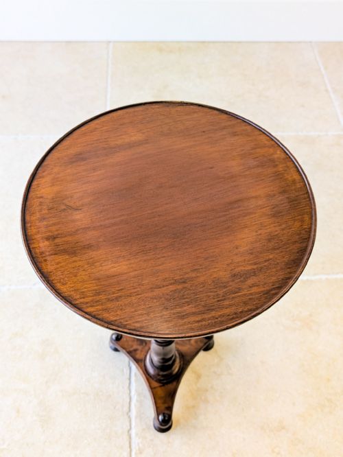 fig 1. An antique Regency mahogany wine table featuring a circular dish top, a slender turned column, and a triform plinth base.