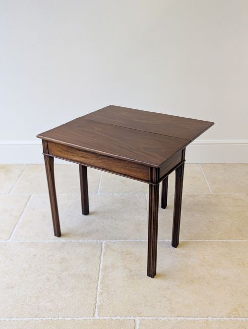fig 1. A late 18th-century George III mahogany fold-over tea table with a rectangular hinged top supported by reeded legs.
