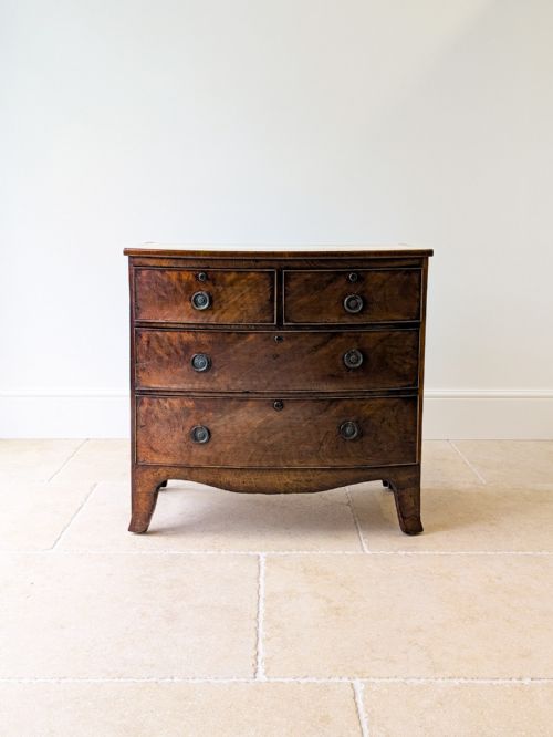 fig 1. An antique Georgian flame mahogany bowfront chest of drawers featuring two short over two long drawers on splayed bracket feet.