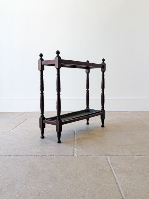 fig 1. A Victorian dark mahogany wooden stick stand featuring turned supports, corner finials, top dividers, and a metal drip tray base.