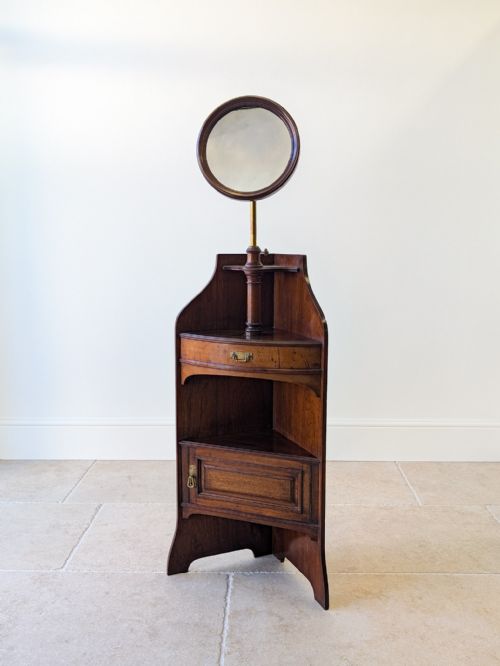 fig 1. A late Victorian dark mahogany corner shaving stand featuring an adjustable circular mirror above a small shelf, drawer, and panelled lower cupboard.