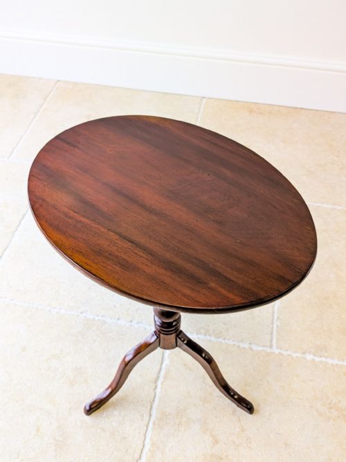 fig 1. An antique Georgian mahogany tilt-top wine table featuring an oval top, turned central column, and a three-legged tripod base.