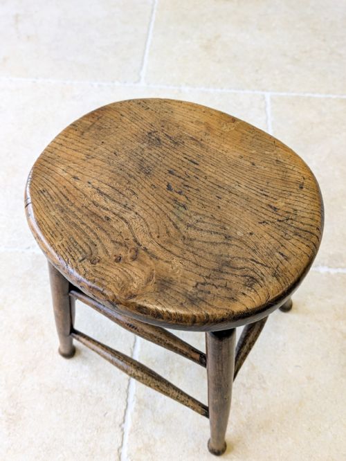 fig 1. A late 19th-century country stool featuring a circular elm seat supported by four turned beech legs joined by spindle stretchers.