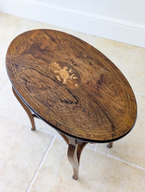 fig 1. An Edwardian oval rosewood occasional table featuring slender cabriole legs, a lower undertier, marquetry inlay on top, and small brass castors.
