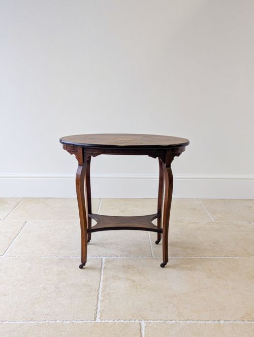 fig 2. An Edwardian oval rosewood occasional table featuring slender cabriole legs, a lower undertier, marquetry inlay on top, and small brass castors.