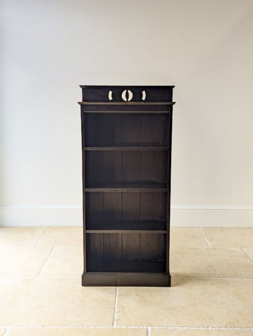 fig 1. A tall, narrow late Victorian dark stained pine bookcase featuring four open shelves, a plank back, and a gallery top with pierced cut-outs.