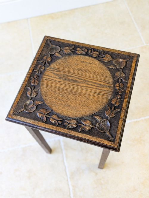 fig 1. A dark oak square occasional table featuring four straight legs and a carved top with a smooth central circular panel.