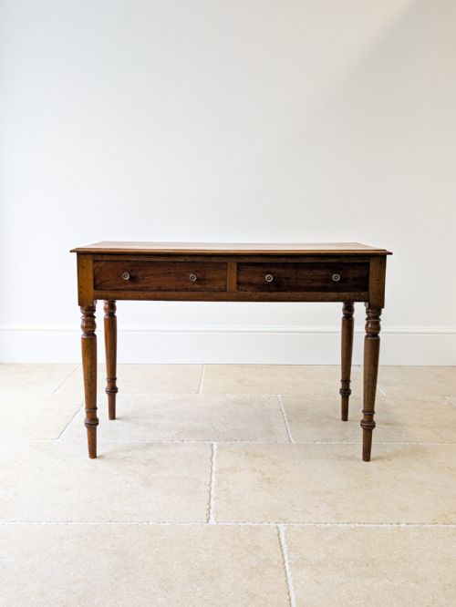 fig 1. A mid-Victorian mahogany writing table featuring two frieze drawers with round knob handles and turned tapered legs.