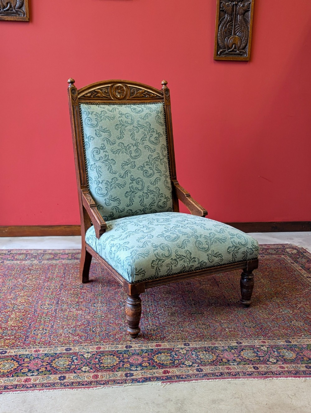 An antique Victorian mahogany easy chair upholstered in patterned teal fabric with carved wooden details and turned front legs. View III