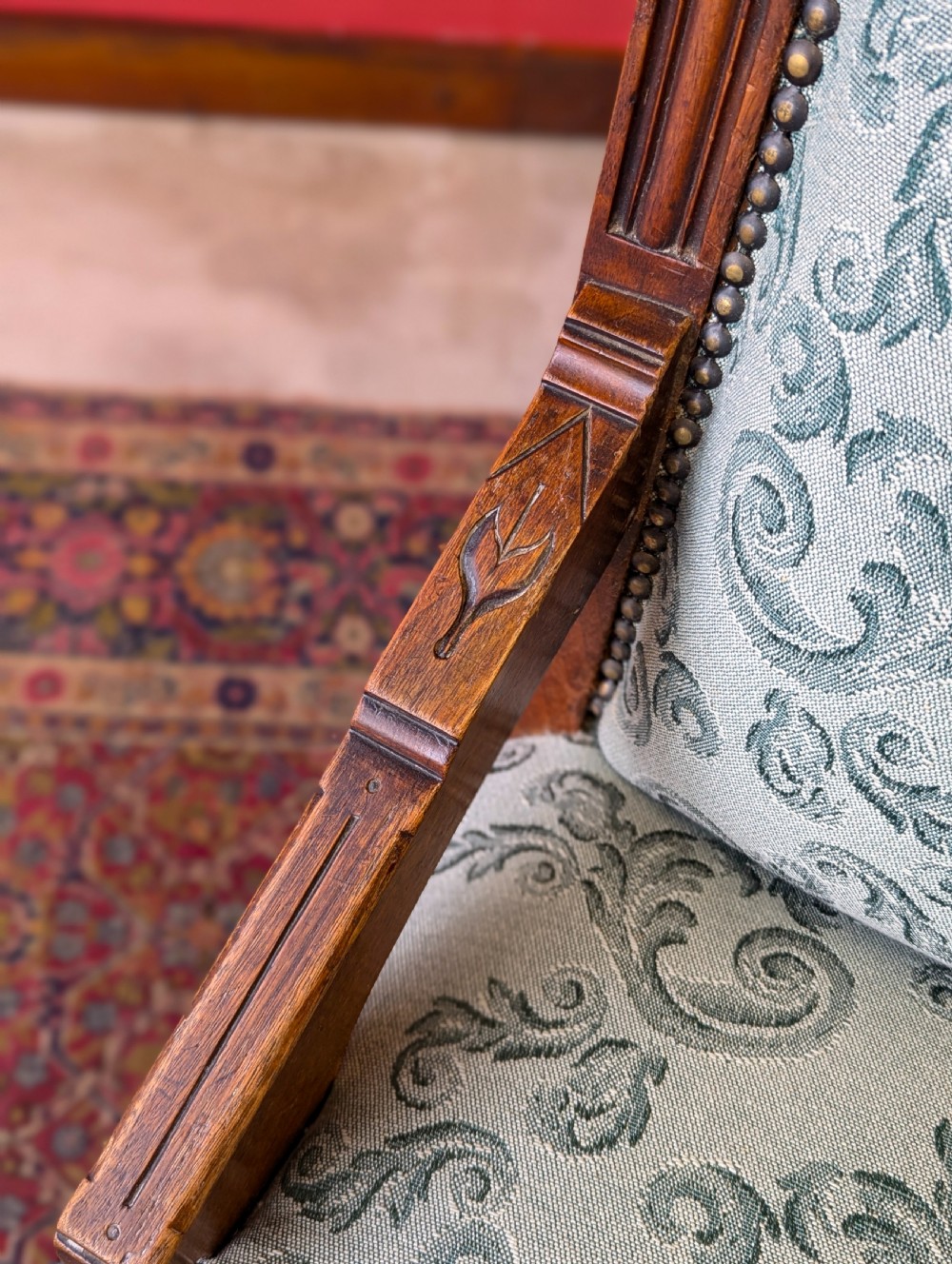 An antique Victorian mahogany easy chair upholstered in patterned teal fabric with carved wooden details and turned front legs. View IV