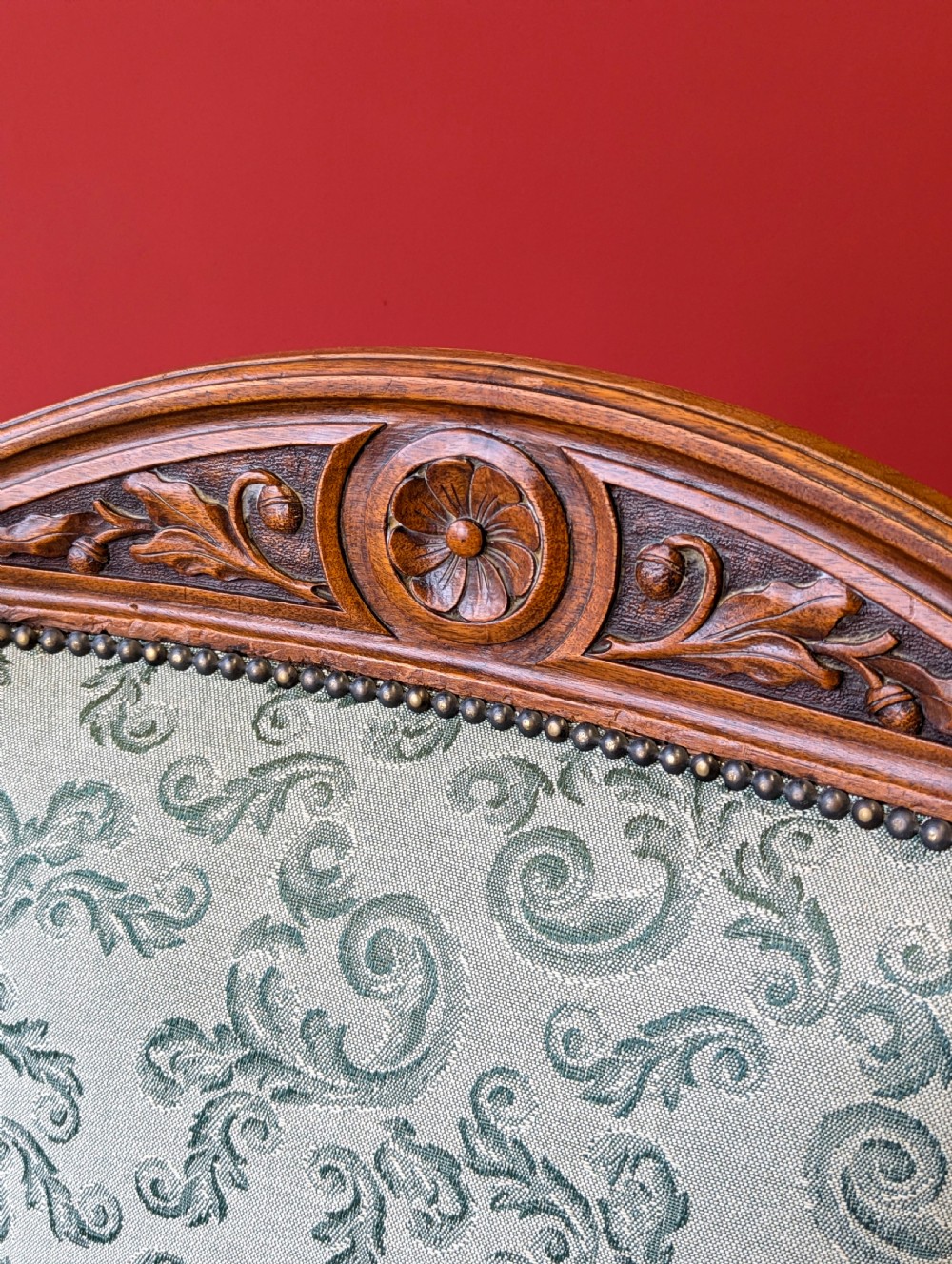 An antique Victorian mahogany easy chair upholstered in patterned teal fabric with carved wooden details and turned front legs. View V