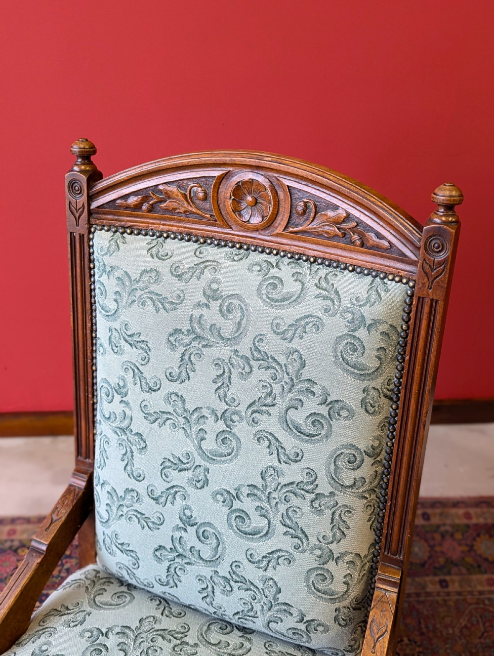 An antique Victorian mahogany easy chair upholstered in patterned teal fabric with carved wooden details and turned front legs. View VI