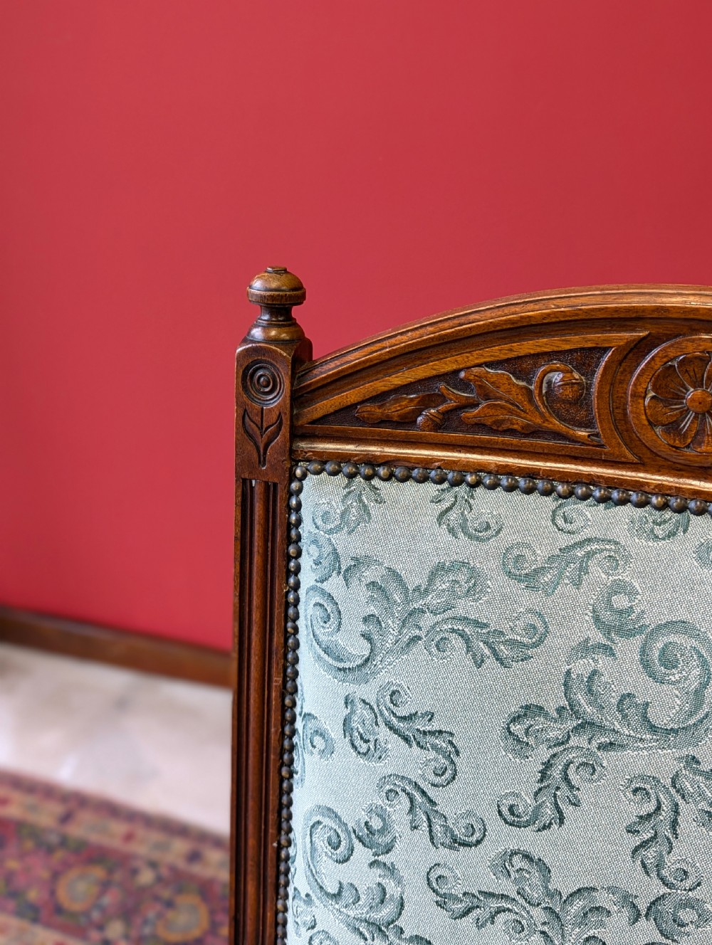 An antique Victorian mahogany easy chair upholstered in patterned teal fabric with carved wooden details and turned front legs. View IX