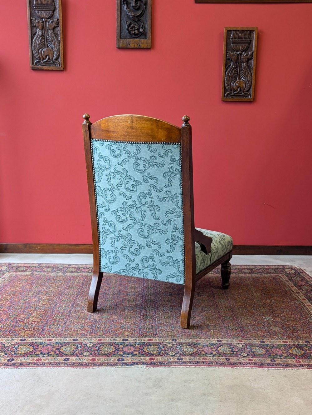 An antique Victorian mahogany easy chair upholstered in patterned teal fabric with carved wooden details and turned front legs. View X