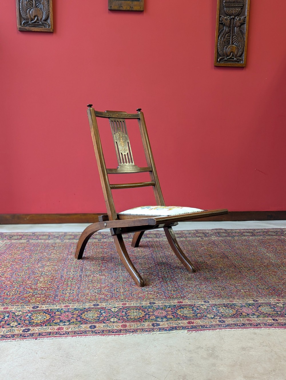 An antique Edwardian folding campaign chair made of mahogany featuring marquetry inlay and an upholstered seat pad. View IV