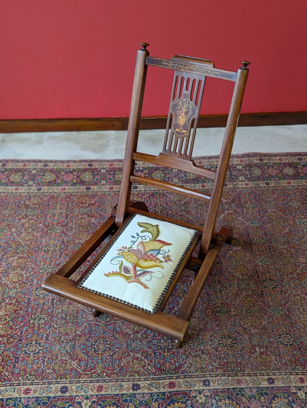 An antique Edwardian folding campaign chair made of mahogany featuring marquetry inlay and an upholstered seat pad. View V