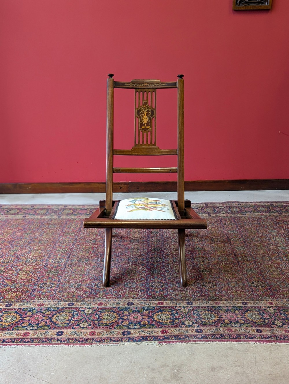 An antique Edwardian folding campaign chair made of mahogany featuring marquetry inlay and an upholstered seat pad. View VI