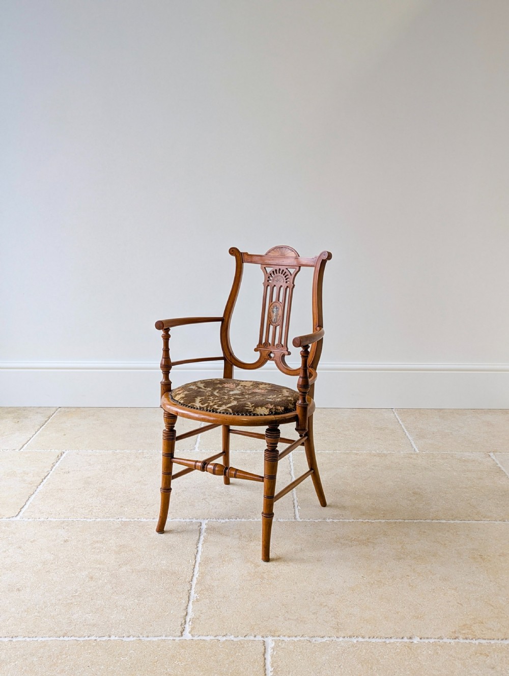 A late Victorian satinwood elbow chair featuring a lyre-shaped backrest with a painted central medallion, turned front legs, and an upholstered seat. View XI