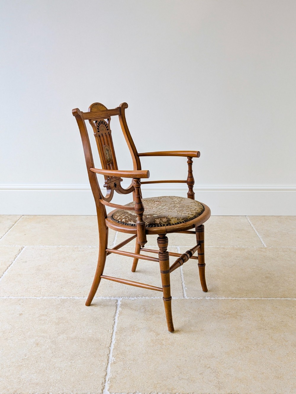 A late Victorian satinwood elbow chair featuring a lyre-shaped backrest with a painted central medallion, turned front legs, and an upholstered seat. View XIII